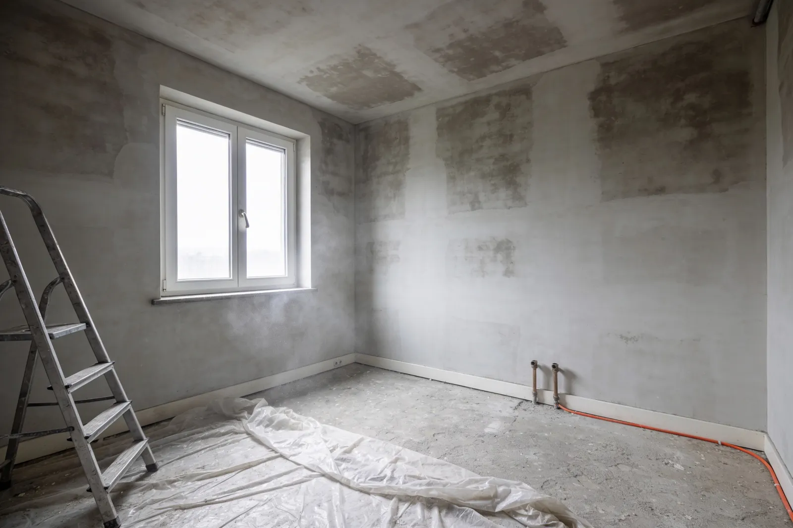 Mur intérieur fini à l'enduit à la chaux, sous une poutre ancienne